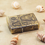 Angled detail of the Grotto Buddha Zippo Armor lighter and its engraved brass finish