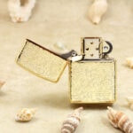Open front of the golden arabesque lighter showing gold-tone chimney and serial panel