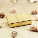 Golden Zippo lying flat with engraved hinge side and lid top visible