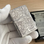 Angled front view of silver-tone arabesque decoration and numbered Zippo panel