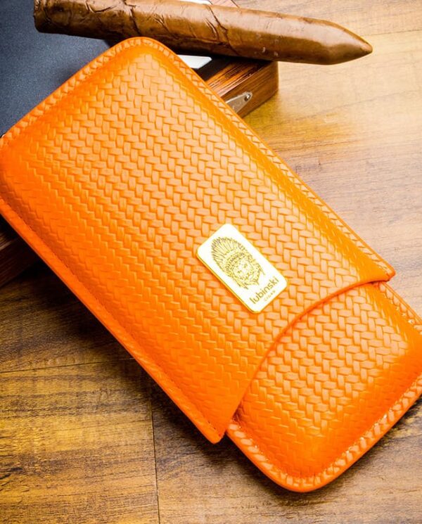 Orange woven leather wallet with a gold Lubinski brand plaque on a wooden table surface.