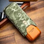 Cigar with a green embossed leather sleeve resting on a wooden surface, Lubinski branding visible on the wood.