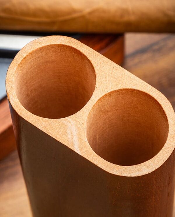 YJA-50029-02 Two adjacent hollow cylindrical holes carved in light wood, forming a twin-hole block seen from an angled top view.