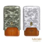 Two Lubinski cigar accessories with leather-textured sleeves (green left, gray right) mounted on wooden bases, shown side by side with the Lubinski Cigar & Pipe logo.
