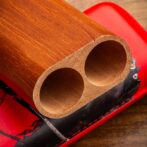 Close-up of a wooden block with two round hollow cylinders resting on a red leather surface.