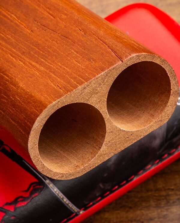 YJA-50031-02 Close-up of a wooden block with two round hollow cylinders resting on a red leather surface.