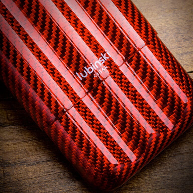 Close-up of a red carbon-fiber patterned phone case with white diagonal stripes on a wooden surface.