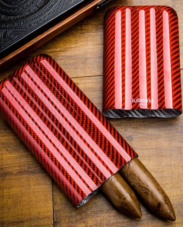 Red carbon-fiber cigar cases with pink stripes on a wooden surface; one opened to reveal two cigars, the other standing upright nearby.