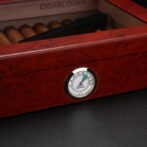 Close-up of a round hygrometer on a red-brown wooden cigar humidor, showing humidity around 60%.