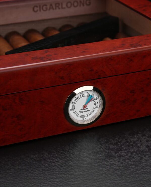Close-up of a round hygrometer on a red-brown wooden cigar humidor, showing humidity around 60%.