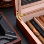 Open wooden cigar humidor with several cigars arranged in a divider and a brass hinge.