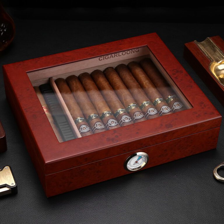 Wooden cigar humidor with glass top displaying a row of cigars and a hygrometer on the front.