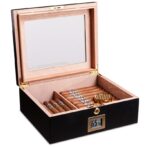 Open wooden cigar humidor with a glass lid, cigars arranged in rows inside and a digital humidity display on the front showing 65%.