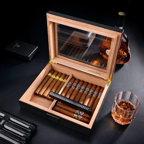CH025-01 Open wooden cigar humidor showing a row of cigars, some with yellow bands, and a built-in humidifier; whiskey bottle and glass nearby.
