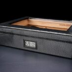 Carbon‑fiber textured cigar humidor with a digital hygrometer showing 69% humidity.