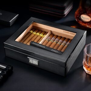 Open premium cigar humidor with two rows of cigars and a digital hygrometer on the front, set on a dark surface beside a bottle and glass.