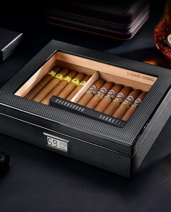 CH025 Open premium cigar humidor with two rows of cigars and a digital hygrometer on the front, set on a dark surface beside a bottle and glass.