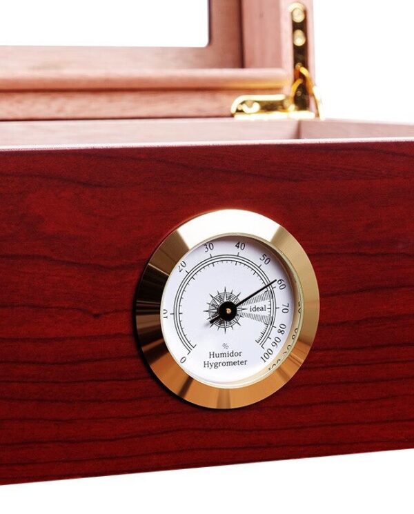 Close-up of a brass-framed hygrometer embedded in dark wood, indicating humidity levels on a humidor surface.