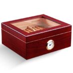 Wooden cigar humidor with glass lid, showing cigars inside and a brass hygrometer on the front.