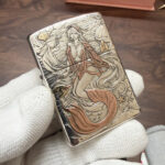 Red-tailed mermaid relief on the sterling silver Zippo Armor case, angled view