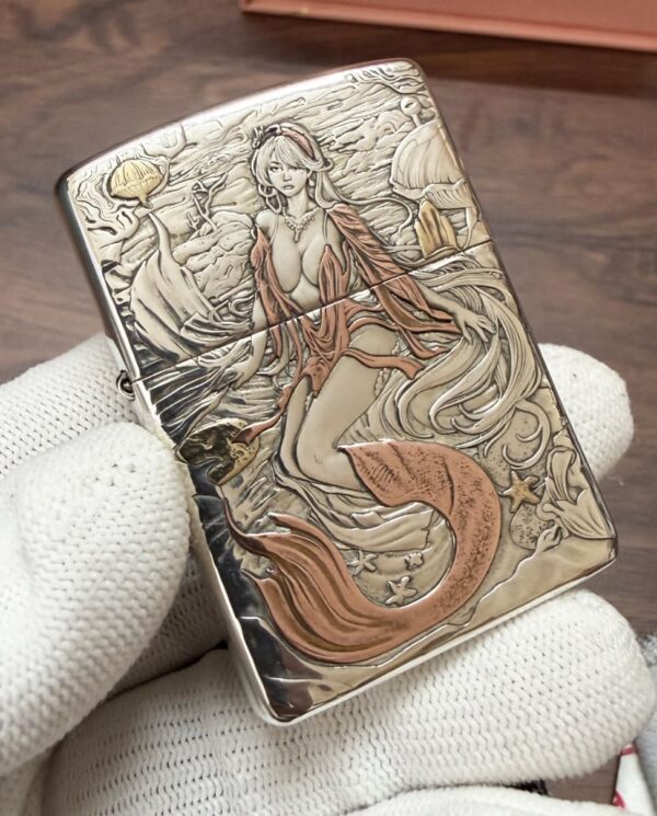 KZ003_05 Engraved metal lighter depicting a mermaid with flowing orange tail underwater, surrounded by shells and starfish on a textured background.
