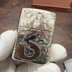Engraved metal lighter with a mermaid in a flowing sea scene.
