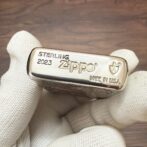 Close-up of a sterling Zippo lighter engraved with 'STERLING 2023 Zippo Made in USA' being held by gloved fingers