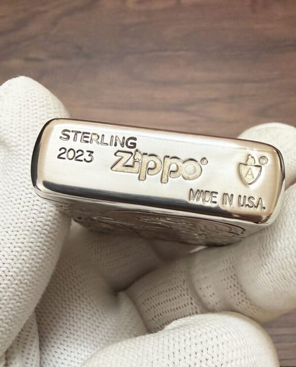 KZ003_11 Close-up of a sterling Zippo lighter engraved with 'STERLING 2023 Zippo Made in USA' being held by gloved fingers