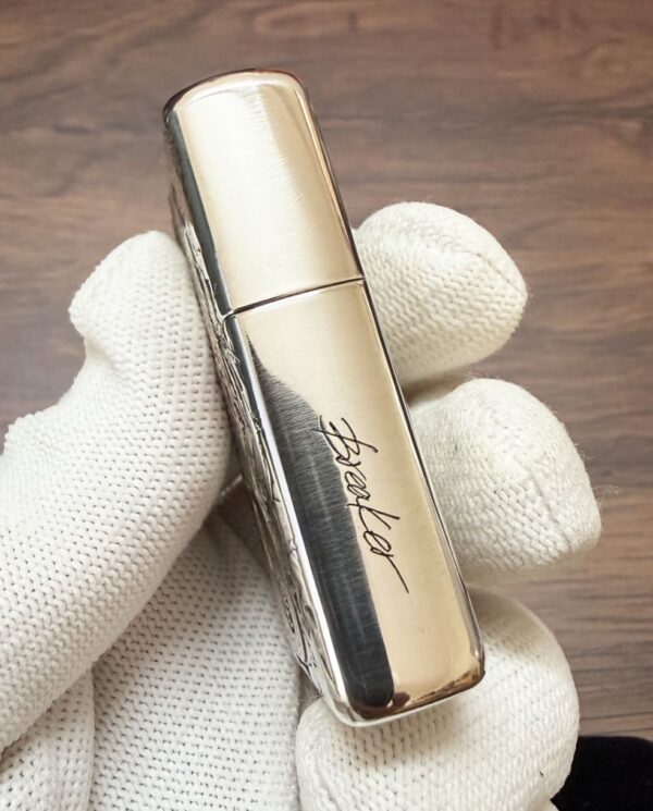 KZ003_18 Close-up of a gold, reflective lipstick tube held by a gloved hand.