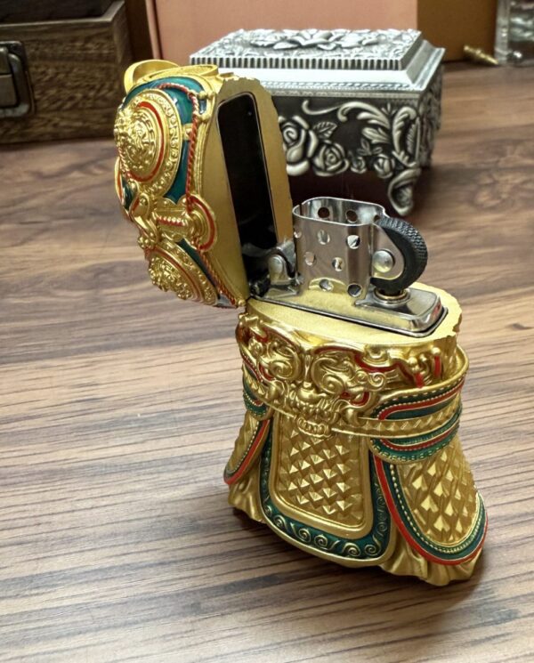 Ornate, gold-toned lighter shaped like a decorative boot with intricate designs and a hinged lid.