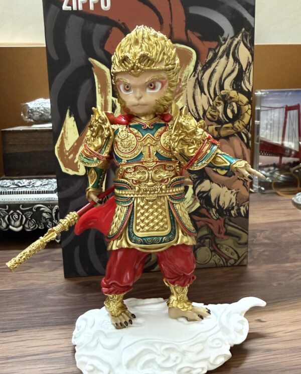 Small collectible figure of a warrior in ornate gold armor with red pants, holding a gold staff, standing on a white decorative base.