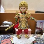 Ornate statue of the Monkey King in gold armor with a long ornate staff, standing on a white cloud base.