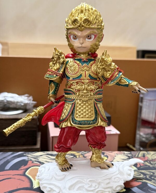 Ornate statue of the Monkey King in gold armor with a long ornate staff, standing on a white cloud base.