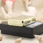 Beauty and Skull brass Zippo Armor lighter displayed on its black Zippo box