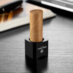 Black CigarLoong stainless steel cigar rest supporting a cigar