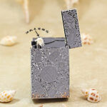 Karl Wieden KW-T0293A open petrol lighter showing wick-style mechanism and chrome silver-tone auspicious-symbol design