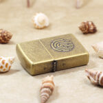 Zippo Classic fingerprint lighter lying flat showing antique brass-tone finish